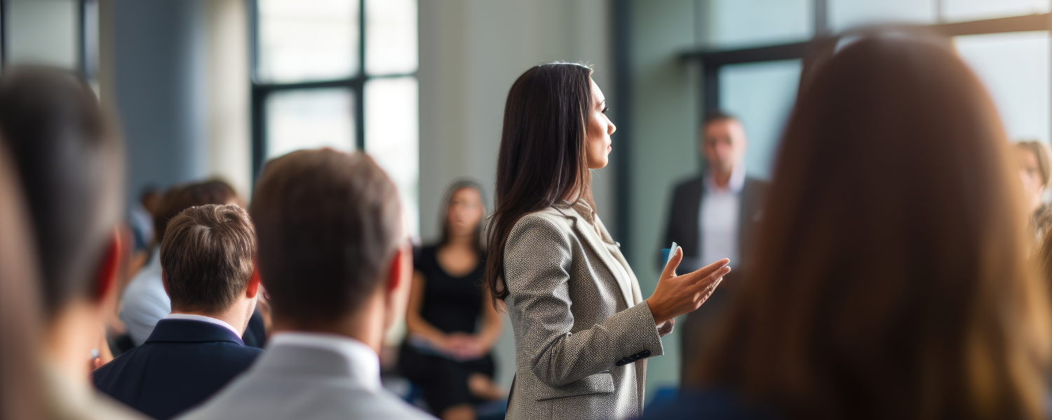Führungskraft spricht vor einer Gruppe von Mitarbeitenden in einem modernen Büro – verschiedene Führungsstile im Vergleich