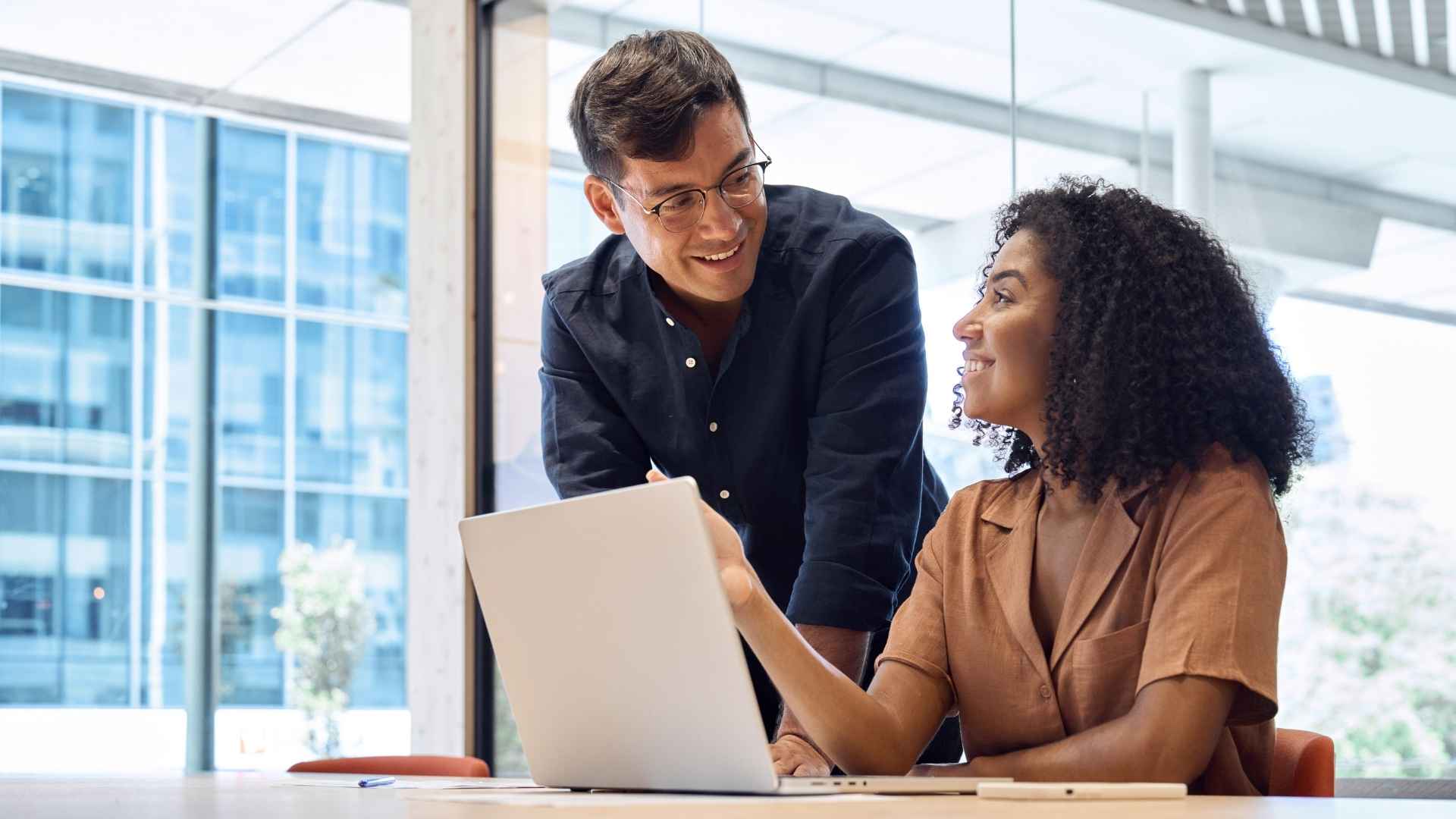 Zwei Consultants besprechen Finanzstrategien am Laptop in einem modernen Büro