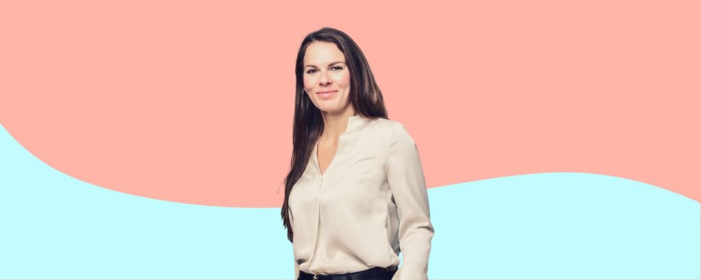 Leonie Westerburg, Senior Managerin bei Consistency, lächelt in heller Bluse vor einem rosa-hellblauen Hintergrund.